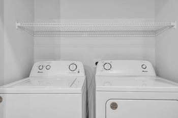 Two white front loading washing machines in a laundry room.